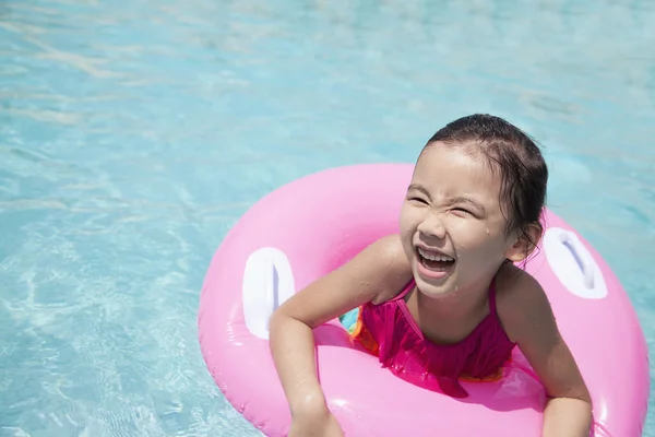 Chica nadando en la piscina con un tubo rosa — Foto de Stock