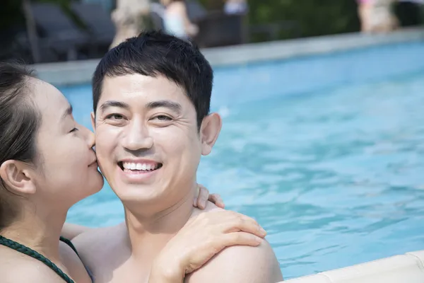 Casal beijando e olhando para a câmera na piscina — Fotografia de Stock