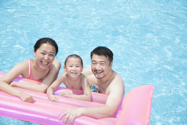 Familia feliz flotando en la piscina en una balsa inflable — Foto de Stock