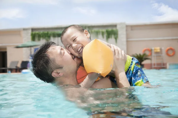 Gülümseyen oğlunu havuzda kucaklayan baba — Stok fotoğraf