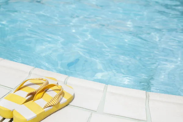Paar van gele flip flops door het zwembad kant — Stockfoto