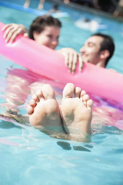 Friends in a pool holding onto an inflatable raft