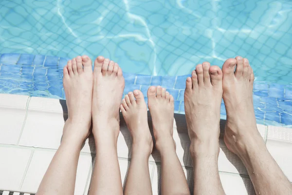 Drie mensen benen door de zwembad kant — Stockfoto