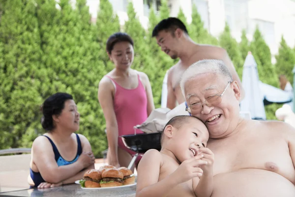 Family barbequing by the pool on vacation — Stock Photo, Image