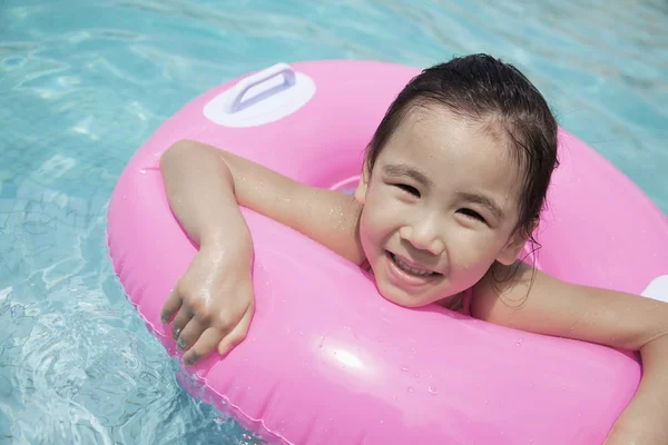 Mädchen schwimmt im Pool mit einem rosa Schlauch — Stockfoto