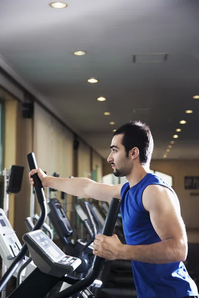 Muscular man exercising on a cross trainer — Stock Photo, Image