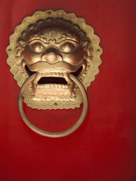 Ornate gold door knocker on red door — Stock Photo, Image