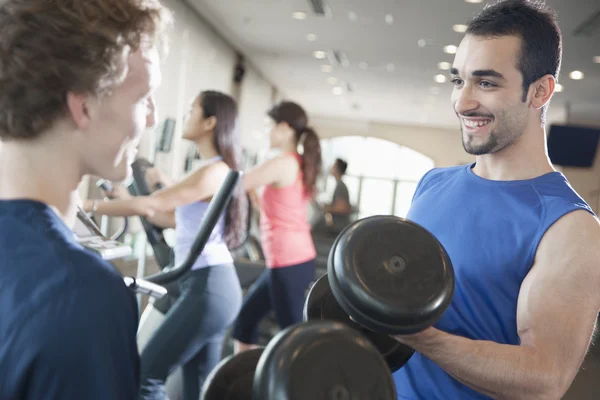 Män ler och lyfta vikter i gymmet — Stockfoto