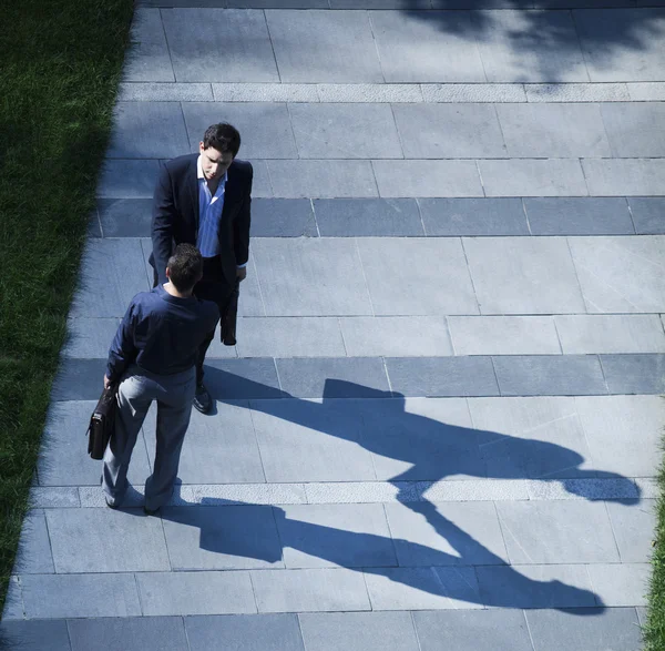 Двое бизнесменов пожимают руки на тротуаре — стоковое фото