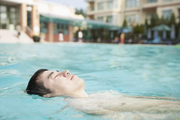 轻松的男子在游泳池中漂浮 — 图库照片