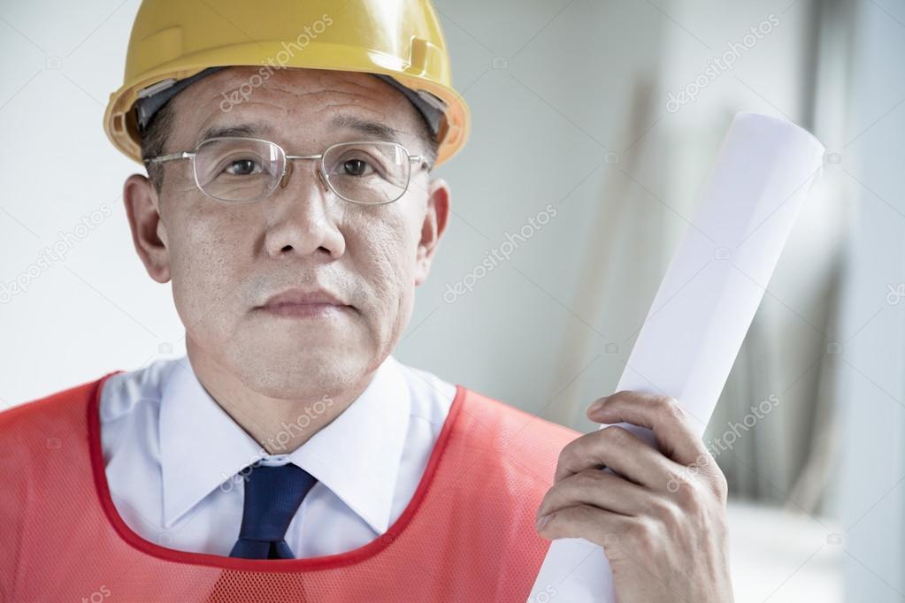 Architect holding a rolled up blueprint indoors