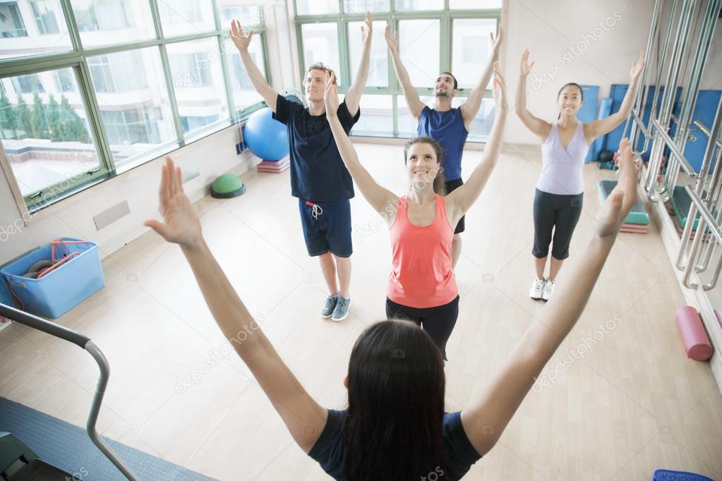 People with hands in the air in a yoga class