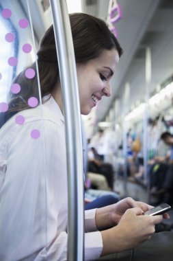 Metro'da oturan ve telefonunu kullanarak iş kadını
