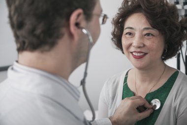 Doctor checking heartbeat of a patient clipart