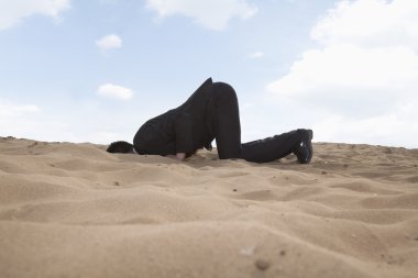 Onun kafasında bir delik kum ile diz çökmüş işadamı