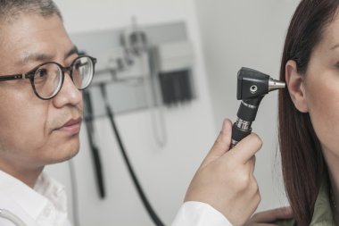 Doctor checking the ears of a patient clipart