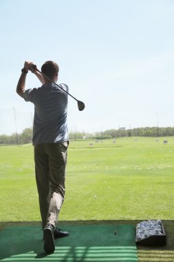Adam golf sahasında golf topları vurmak