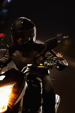 Man riding a motorcycle at night clipart
