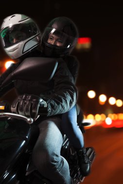 Couple riding a motorcycle at night clipart