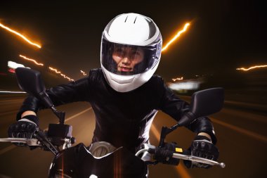 Woman riding a motorcycle through the streets clipart