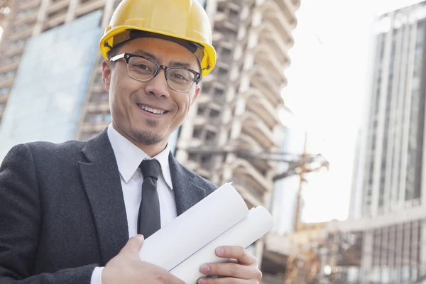 Architect on site carrying blueprints — Stock Photo, Image