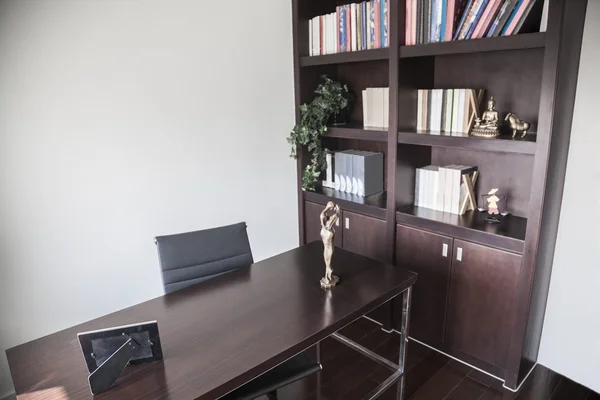 Современный домашний офис с книжными полками и скульптурами — стоковое фото