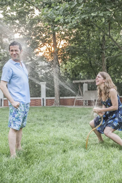 Pareja jugando con una manguera de jardín — Foto de Stock