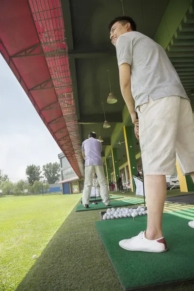 Mann schwingt und schlägt Golfbälle auf dem Golfplatz — Stockfoto