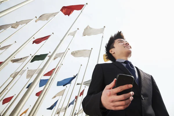 Бизнесмен держит телефон с флагами — стоковое фото