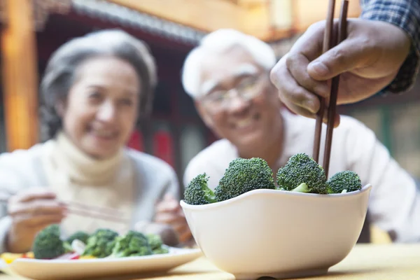 Hand picking up broccoli with chopsticks — Stock Photo, Image