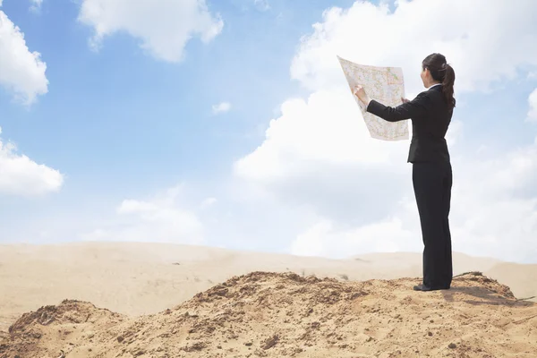 Businesswoman looking at a map in the desert — Stock Photo, Image