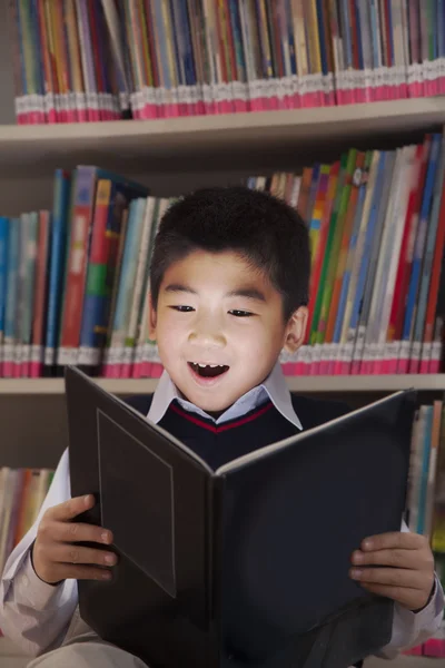 Schooljongen lezen van een boek met haar gezicht verlicht — Stockfoto