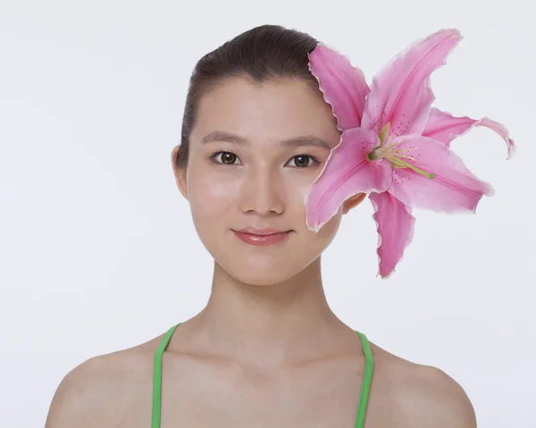 彼女の耳の後ろに隠れている大きなピンクの花を持つ女性 — ストック写真