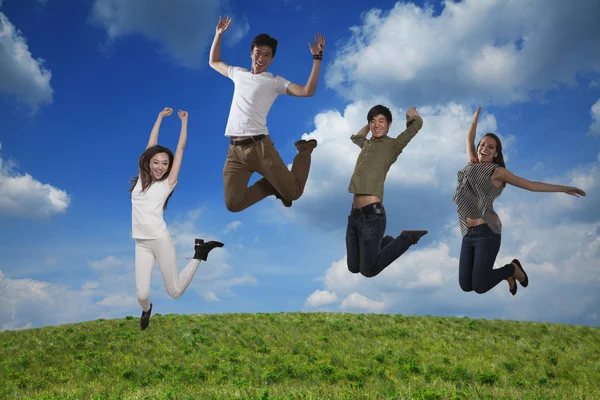 Four smiling friends jumping — Stock Photo, Image