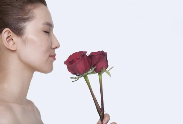 目を持つ女性閉じた赤いバラの香り — ストック写真