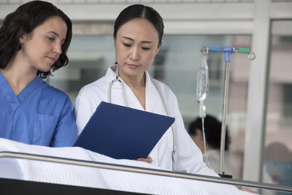 Doctor looking down at the medical record of patient — Stock Photo, Image