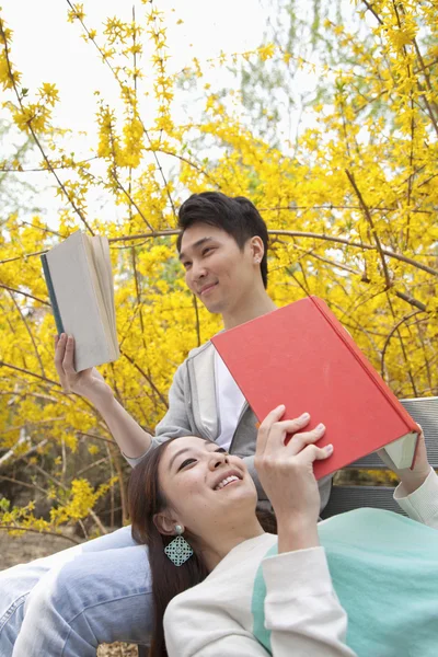 Casal em um banco de parque gostando de ler seus livros — Fotografia de Stock