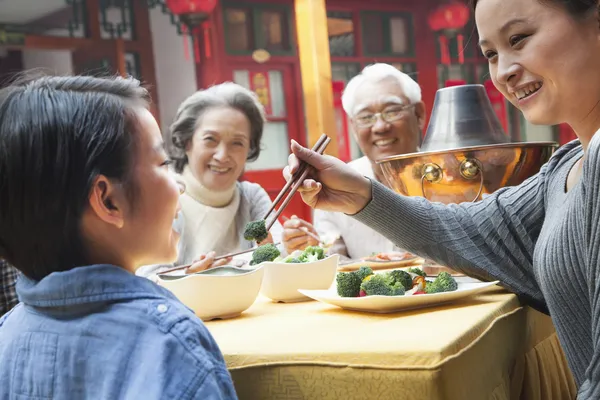 Mother feeding daughter broccoli during a meal — Stock Photo, Image