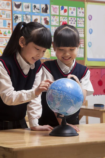 Schülerinnen schauen im Klassenzimmer auf eine Weltkugel — Stockfoto