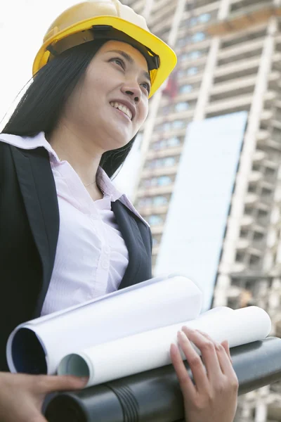 Female architect on site carrying blueprints — Stock Photo, Image