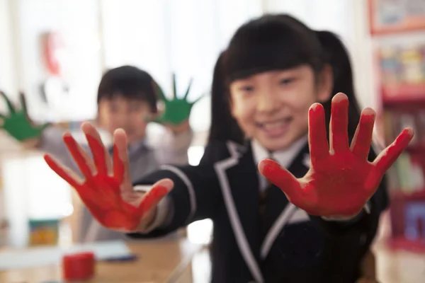 Skolbarn visar händerna täckta i paint — Stockfoto