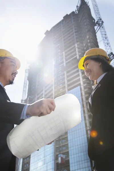 Two architects at a construction site holding blueprint — Stock Photo, Image