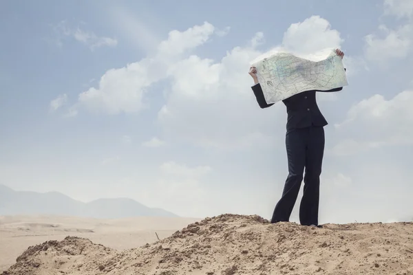 Mulher de negócios olhando para um mapa no meio do deserto — Fotografia de Stock