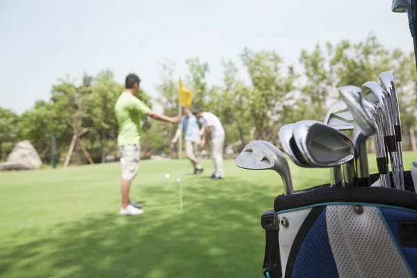 Tres amigos jugando al golf en el campo de golf —  Fotos de Stock