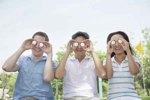 Freunde in einer Reihe halten Golfbälle vor ihren Augen hoch — Stockfoto