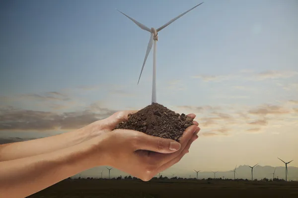 Hands holding soil with a wind turbine — Stock Photo, Image