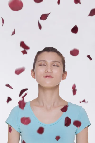 Woman with rose petals flying around her — Stock Photo, Image