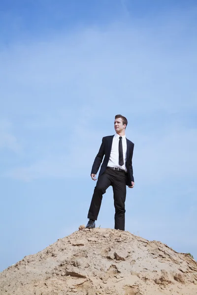 Solitary businessman standing on a hill in the desert — Stock Photo, Image