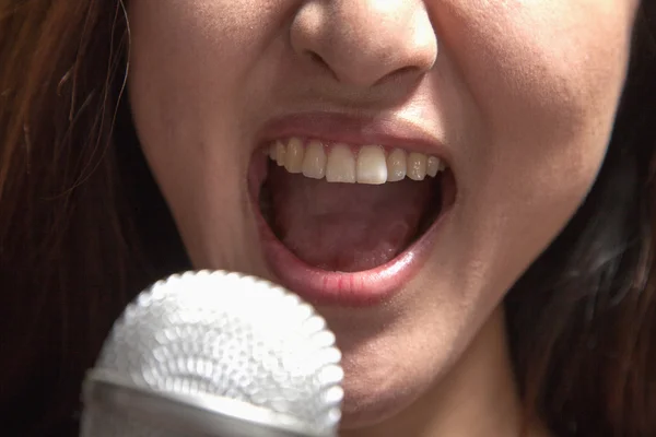 Kobieta śpiewa do mikrofonu w karaoke — Zdjęcie stockowe