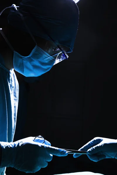 Surgeons working and passing surgical equipment — Stock Photo, Image